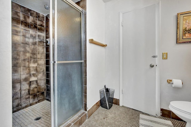 full bath featuring toilet, a stall shower, and tile patterned floors