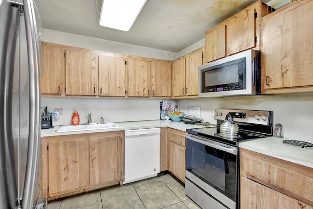 kitchen with appliances with stainless steel finishes, light brown cabinets, light countertops, and a sink