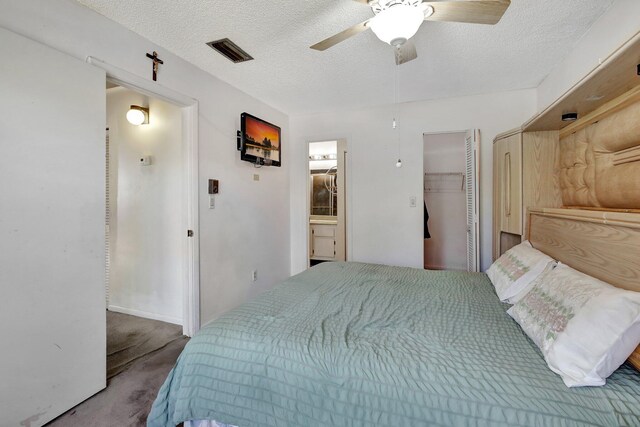 bedroom featuring ceiling fan, ensuite bathroom, carpet flooring, visible vents, and a textured ceiling