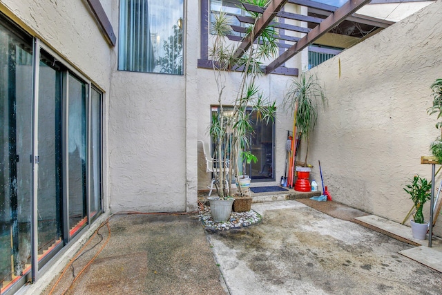 property entrance featuring stucco siding and a pergola