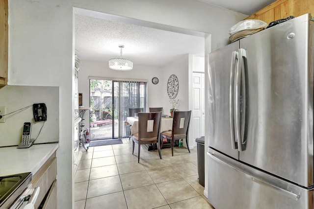 kitchen with light tile patterned floors, a textured ceiling, appliances with stainless steel finishes, light countertops, and decorative light fixtures