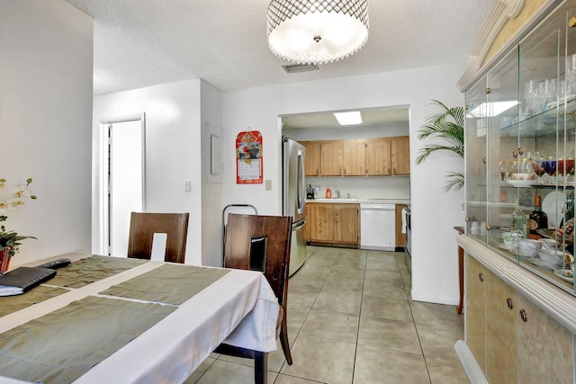 dining room featuring light tile patterned floors, visible vents, and a textured ceiling