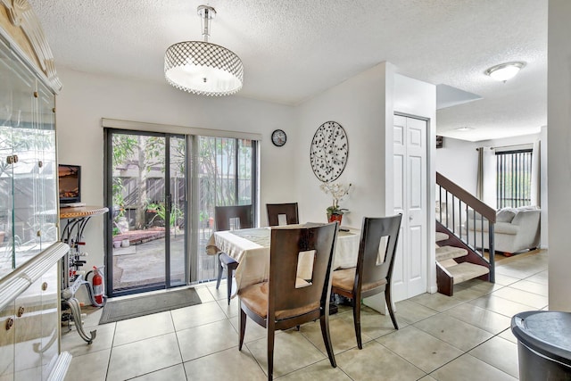 dining room with light tile patterned floors, a textured ceiling, and stairs