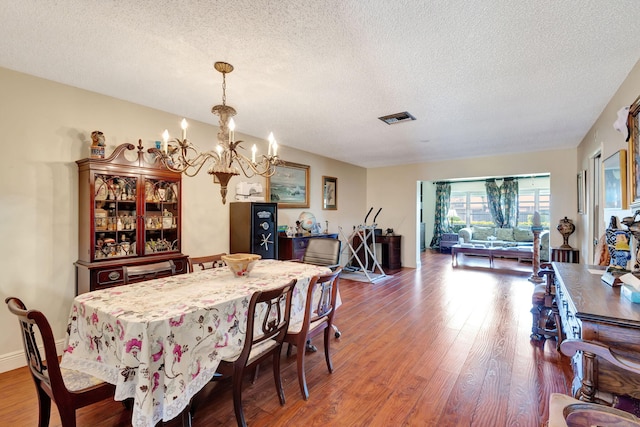 5800 Fernley Dr W Unit 45, Greenacres, FL 33415 - dining area featuring visible vents, wood finished floors, an inviting chandelier, and a textured ceiling