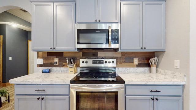 551 SW Lairo Ave, Port Saint Lucie, FL 34953 - kitchen with tasteful backsplash, stainless steel appliances, light countertops, and arched walkways