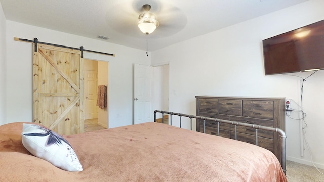 551 SW Lairo Ave, Port Saint Lucie, FL 34953 - bedroom with connected bathroom, a barn door, carpet, baseboards, and visible vents