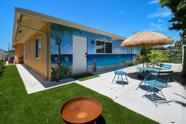 951 Green St, West Palm Beach, FL 33405 - rear view of house with stucco siding, a patio, a lawn, and central AC unit
