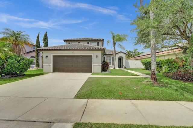 mediterranean / spanish-style home with a front lawn, stucco siding, a tiled roof, concrete driveway, and an attached garage