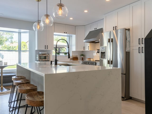 kitchen with recessed lighting, under cabinet range hood, backsplash, white cabinets, and appliances with stainless steel finishes