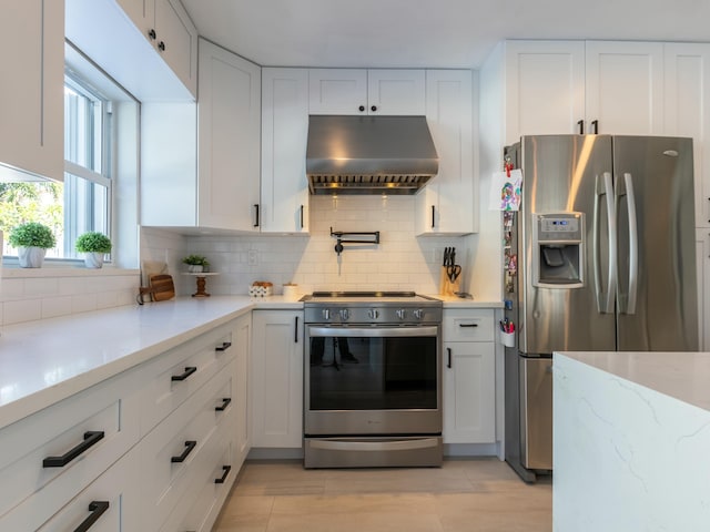 kitchen featuring light stone counters, decorative backsplash, white cabinets, stainless steel appliances, and ventilation hood