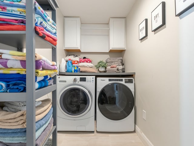 clothes washing area with baseboards, cabinet space, washing machine and clothes dryer, and light wood-style floors
