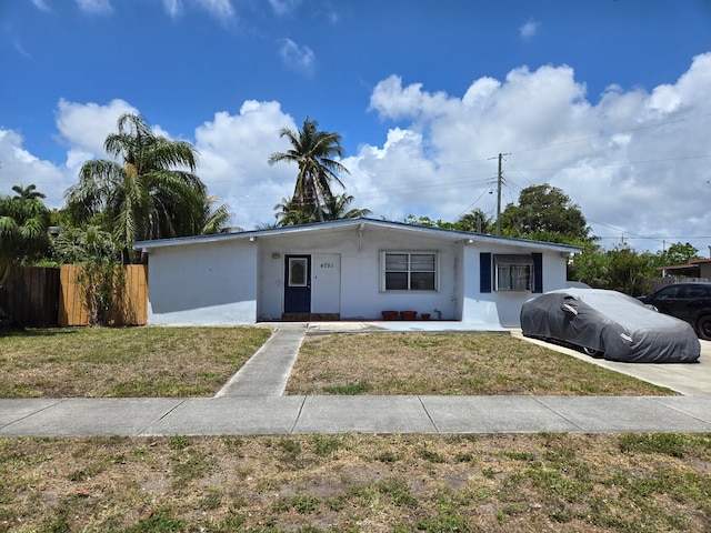 view of front of house featuring stucco siding, a front lawn, and fence