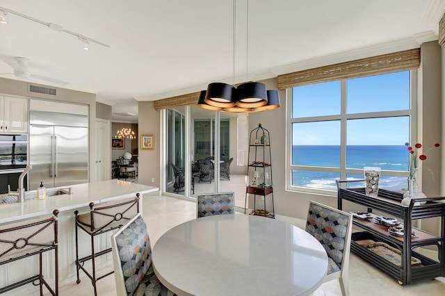 3740 S Ocean Blvd Unit 1602, Highland Beach, FL 33487 - dining space featuring crown molding, rail lighting, ceiling fan with notable chandelier, a water view, and visible vents