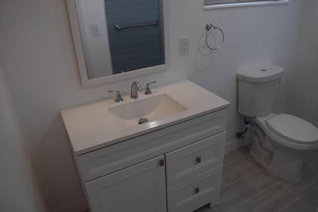 bathroom with baseboards, toilet, and vanity