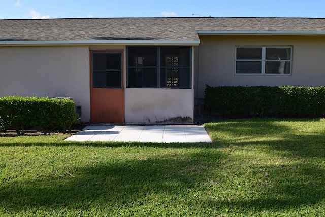 doorway to property featuring a lawn, stucco siding, and roof with shingles