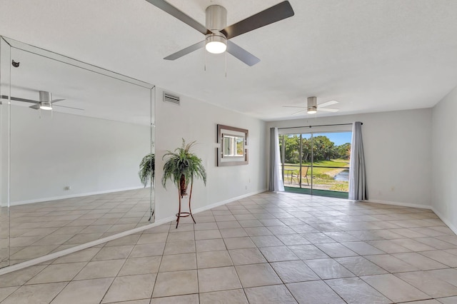 empty room featuring baseboards, ceiling fan, visible vents, and light tile patterned floors
