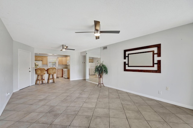 empty room featuring visible vents, a ceiling fan, baseboards, and light tile patterned flooring