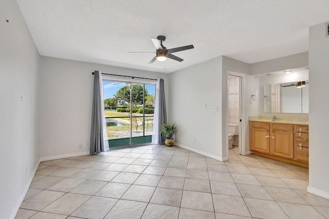 spare room featuring a ceiling fan, baseboards, light tile patterned flooring, and a sink