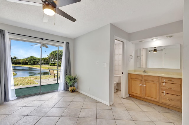 interior space featuring a sink, a water view, ceiling fan, and light tile patterned flooring