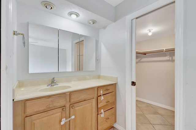 bathroom featuring vanity, tile patterned flooring, baseboards, and a spacious closet