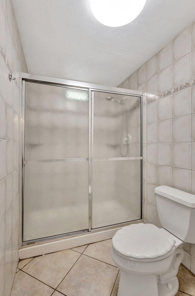 bathroom with tile walls, tile patterned flooring, and a stall shower
