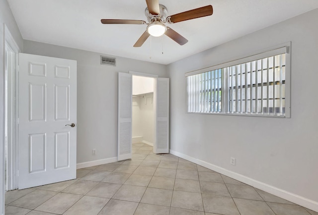 unfurnished bedroom featuring visible vents, a closet, baseboards, tile patterned floors, and a ceiling fan