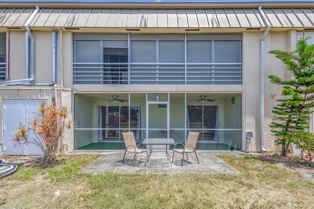 rear view of property featuring ceiling fan, a lawn, a balcony, a patio, and stucco siding