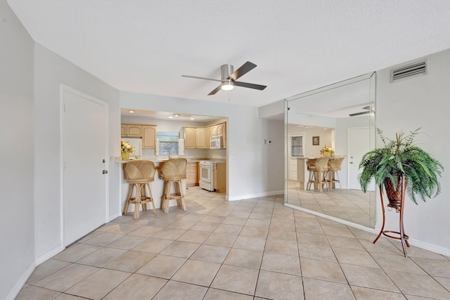 living room with light tile patterned floors, baseboards, a ceiling fan, and visible vents