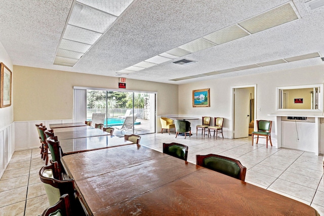 dining area with visible vents, a textured ceiling, wainscoting, and light tile patterned flooring
