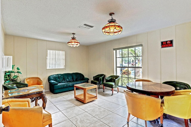 living area featuring a textured ceiling, visible vents, and a decorative wall