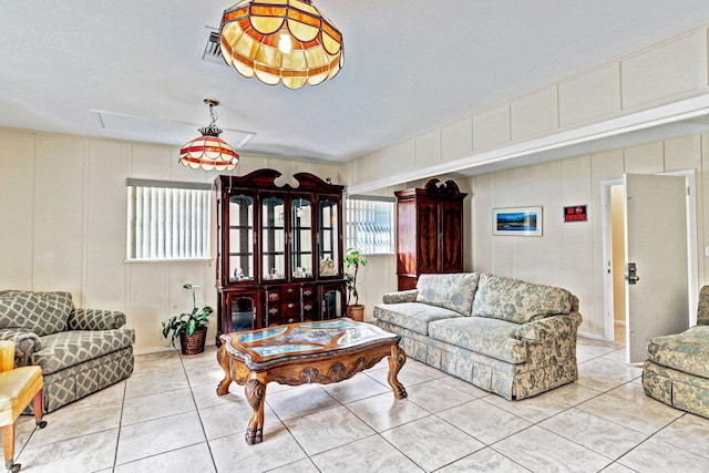 tiled living area with a decorative wall, attic access, and visible vents