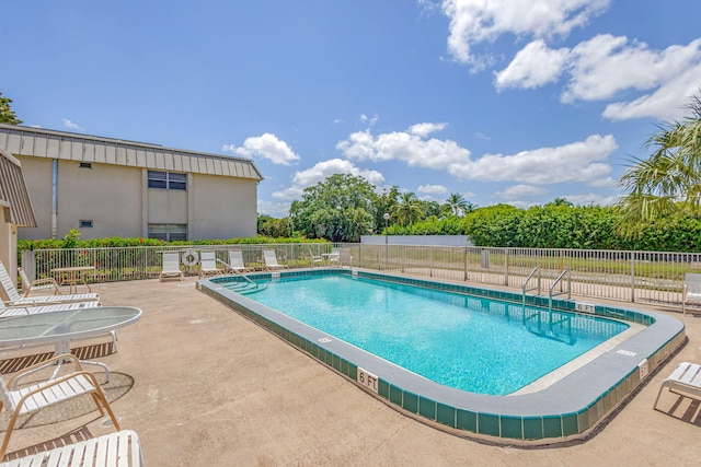 community pool with fence and a patio area