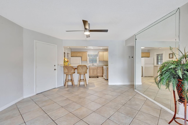 living room with light tile patterned floors, baseboards, and ceiling fan
