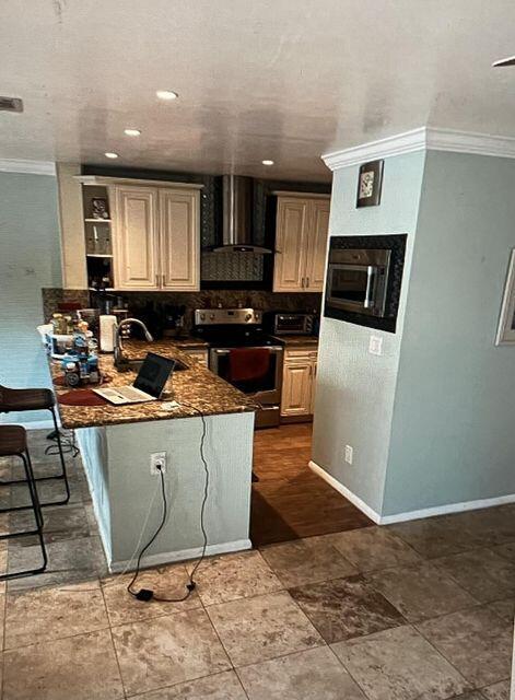 kitchen featuring stainless steel range with electric cooktop, ornamental molding, range hood, baseboards, and a peninsula
