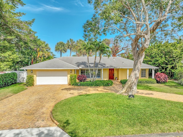 ranch-style house featuring an attached garage, decorative driveway, stucco siding, and a front yard