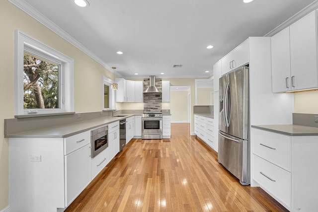 kitchen featuring crown molding, a sink, wall chimney exhaust hood, stainless steel appliances, and visible vents