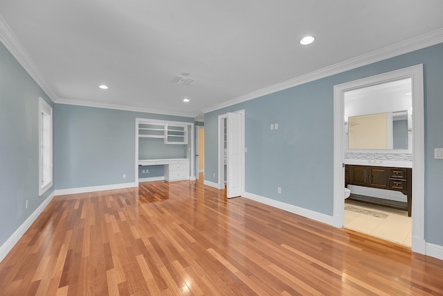 unfurnished living room with baseboards, ornamental molding, light wood-type flooring, and built in desk