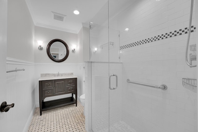 full bathroom with crown molding, vanity, toilet, a wainscoted wall, and a stall shower