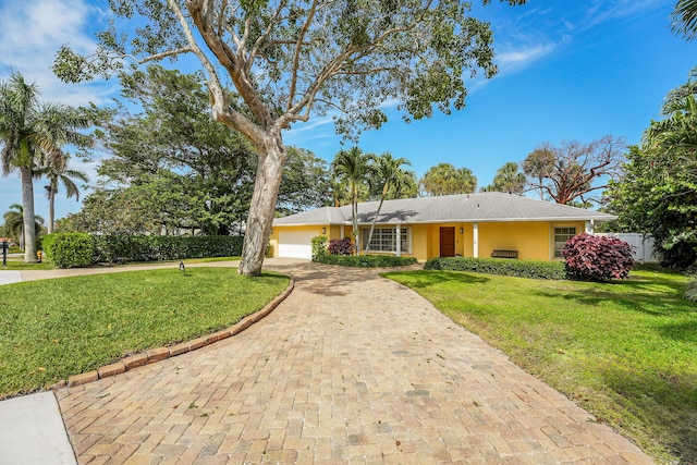 ranch-style home featuring a garage, stucco siding, decorative driveway, and a front yard