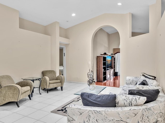 tiled living area featuring arched walkways, baseboards, recessed lighting, and lofted ceiling