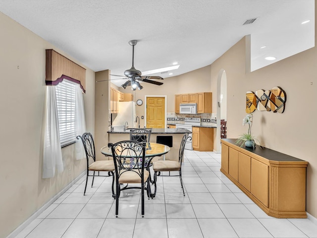 dining space featuring light tile patterned flooring, arched walkways, a ceiling fan, baseboards, and visible vents