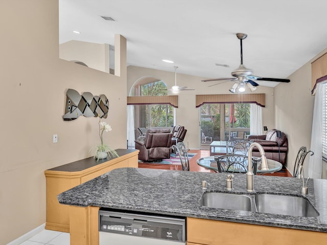 kitchen with a ceiling fan, open floor plan, dishwashing machine, a sink, and vaulted ceiling