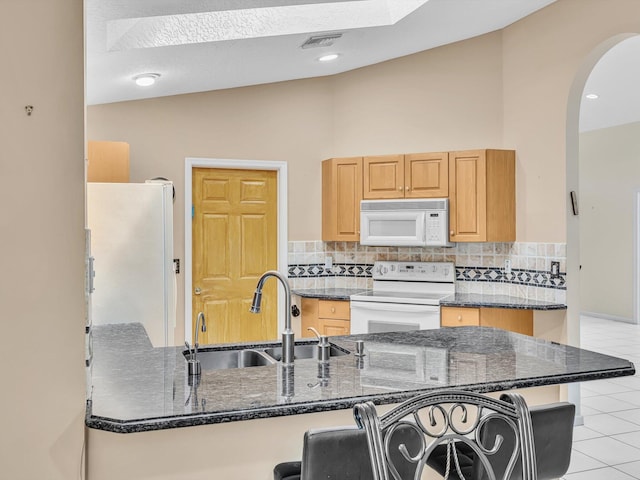 kitchen featuring white appliances, arched walkways, a sink, and backsplash