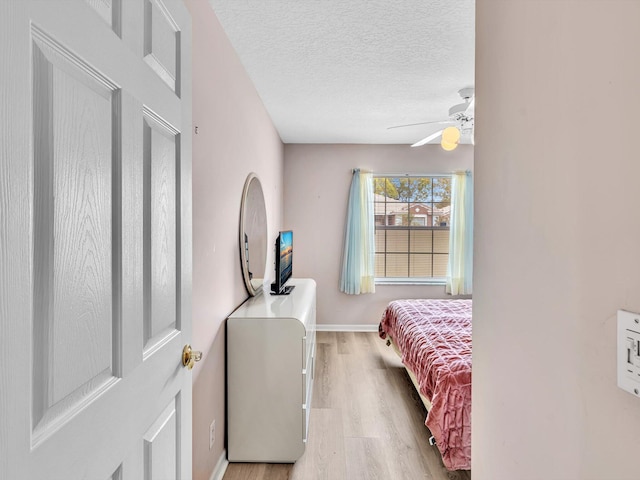 bedroom featuring baseboards, a ceiling fan, a textured ceiling, and wood finished floors