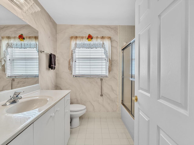 full bath with vanity, bath / shower combo with glass door, tile patterned flooring, and toilet