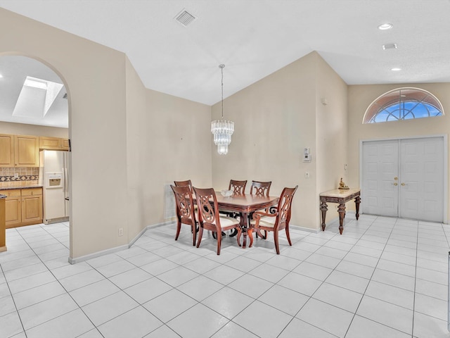 dining space with visible vents, baseboards, arched walkways, light tile patterned floors, and a notable chandelier