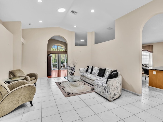 living room featuring arched walkways, visible vents, light tile patterned floors, and lofted ceiling