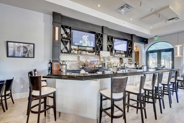 bar featuring visible vents, rail lighting, a community bar, and light wood-type flooring