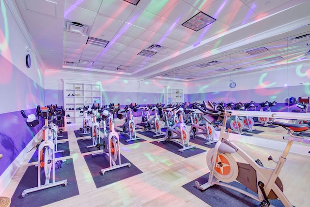 gym featuring wood finished floors, a paneled ceiling, and visible vents
