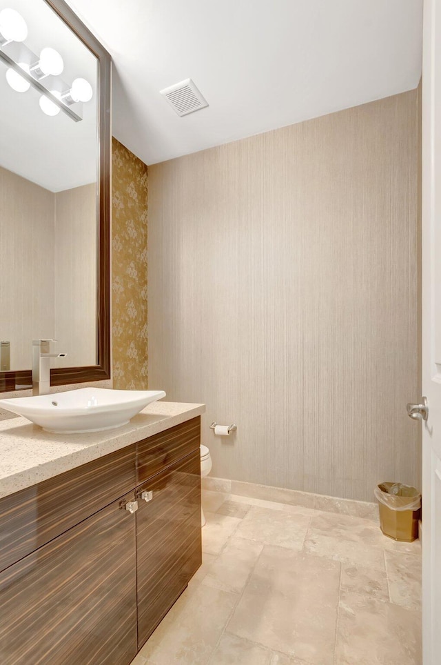 bathroom featuring toilet, visible vents, wallpapered walls, and vanity